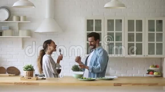 有趣的一对笑着唱歌跳舞一起做饭现代厨房视频的预览图