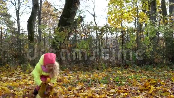 在秋天的花园里小女孩在空中抛出干燥的叶子视频的预览图