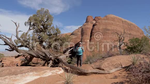 徒步旅行者穿过沙漠在橙色岩石中停留环顾四周视频的预览图