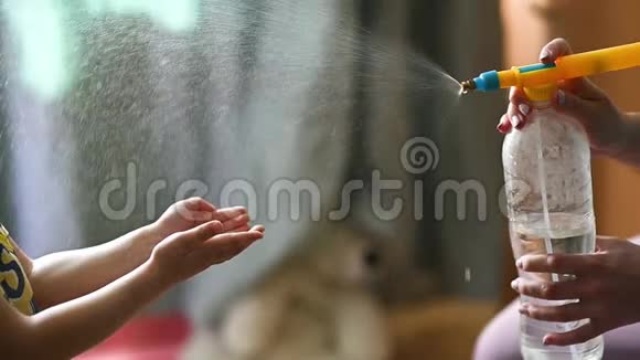 妈妈在她的手上喷洒了一种消毒喷雾剂让她的孩子消毒视频的预览图