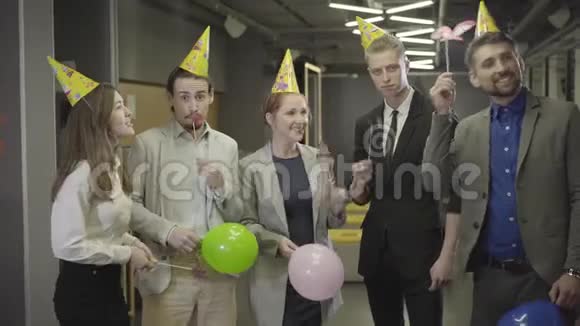 五个积极的白种人办公室工作人员戴着派对帽看着相机在开放空间办公室微笑友好视频的预览图