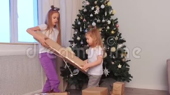 两个姐妹在圣诞树附近互相拿走礼物盒视频的预览图