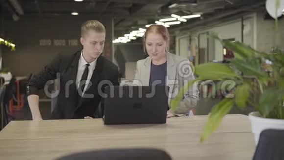 白人青年男女穿着正式服装坐在露天办公室的桌子上使用笔记本电脑的肖像视频的预览图