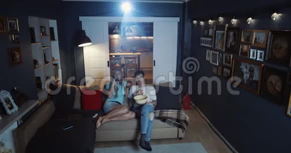 高角度快乐的年轻欧洲朋友男女在家看电影使用投影仪在线影院慢动作视频的预览图