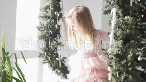 美丽的女孩坐在装饰着圣诞树的秋千上视频的预览图