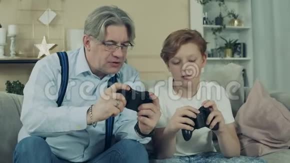 一位老人和他的孙子一起观察游戏机视频的预览图
