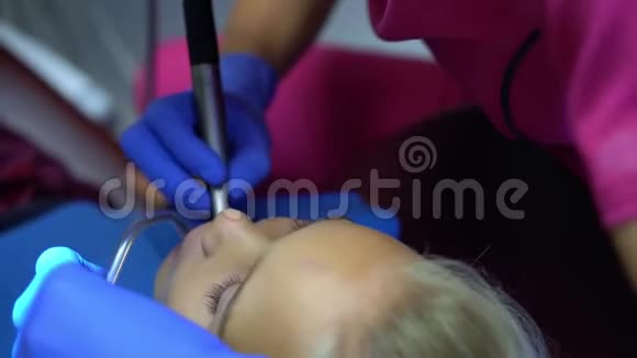 牙医钻子牙金发女孩的脸和穿粉色制服的口腔医生视频的预览图