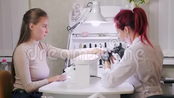 在美容院带手套的女美甲师在涂胶前先把顾客的指甲擦掉视频的预览图