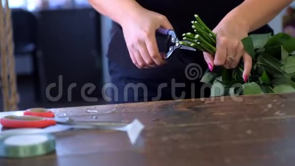 花商妇女准备花束剪玫瑰茎在商店特写的手视频的预览图