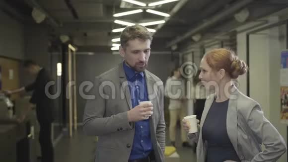 白人男人和女人拿着咖啡杯说话同事在空地办公室休息商务视频的预览图