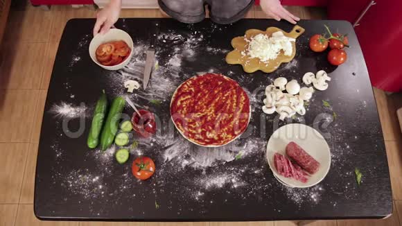 年轻女孩的手把番茄放在披萨面团上视频的预览图
