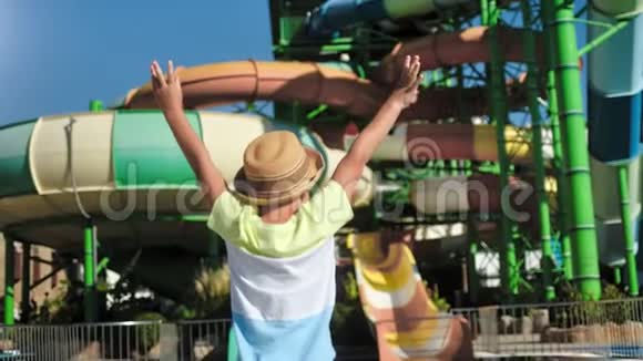 晒太阳的小男孩戴着帽子跳着举起手在户外水上乐园里欢度节日视频的预览图