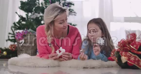 开朗的白种人黑发女孩在家和妈妈一起吃圣诞饼干时做鬼脸幸福的家庭开支视频的预览图