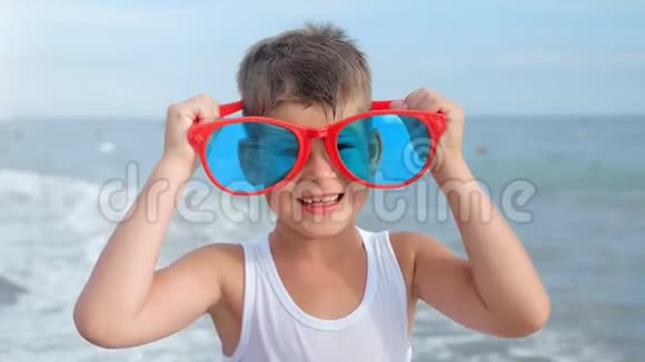 微笑的小旅行者的肖像戴着红色的滑稽眼镜露出冷静的拇指视频的预览图