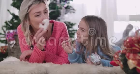 快乐的白人母女躺在柔软的地毯上吃着饼干成年妇女和小女孩视频的预览图