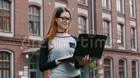 女学生或自由职业者的肖像戴眼镜的妇女站在笔记本电脑上工作大学背景的女孩视频的预览图
