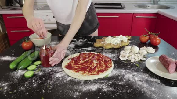 小女孩的手拿着番茄酱涂抹在披萨面团上视频的预览图