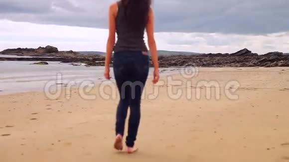 美丽的黑发女郎沿着海边的水走视频的预览图