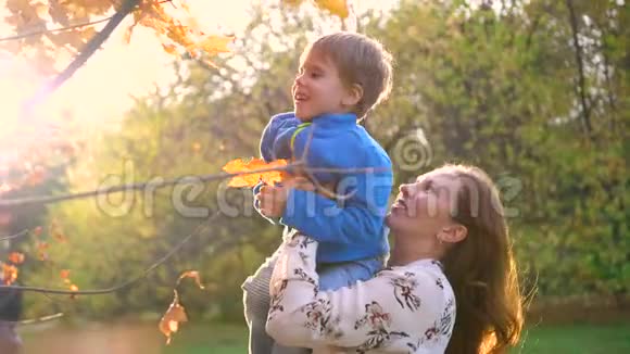 妈妈抱着一个孩子玩把他抱起来阳光穿过孩子欢乐的笑声视频的预览图