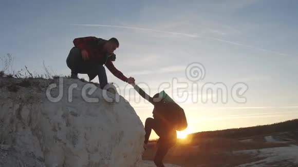 徒步旅行者在山上帮助女朋友登山队员帮助队友攀爬背着背包的人伸出手来视频的预览图