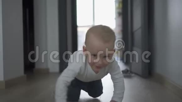 快乐的小男孩爬到木地板上的摄像机前万向节运动视频的预览图