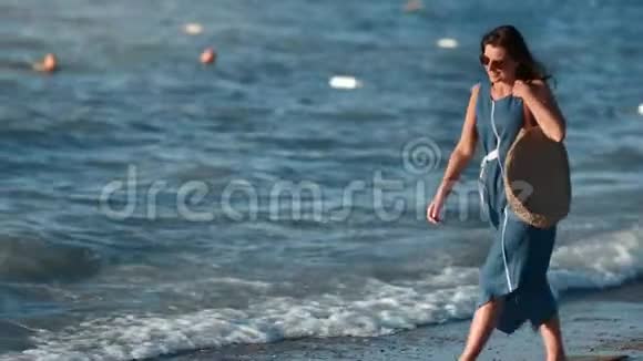 迷人的时尚旅游女性日落时在海浪背景下漫步海滩视频的预览图