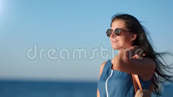 快乐的时尚女孩在日落时在海景背景下摆着摆着摆着摆着的头发视频的预览图