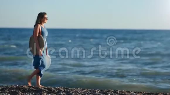 美丽的旅行阳光明媚的赤脚女人在夕阳下的海滩上散步沉思着美丽的自然视频的预览图
