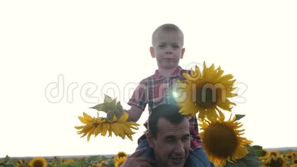 父子俩在清新的空气中行走那个金发孩子坐在他父亲脖子上一个幸福的家庭度过他们的休息日视频的预览图