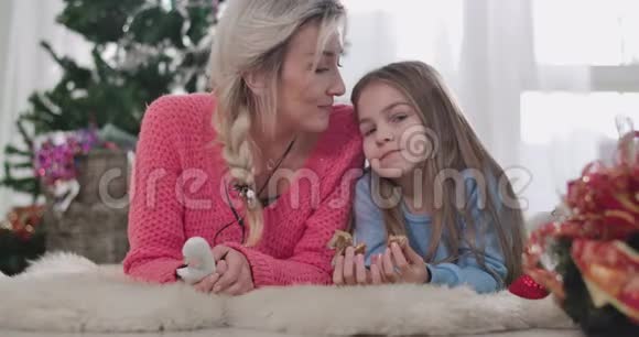 年轻白种人母亲亲吻女儿额头的特写肖像金发成年女人和黑发女孩视频的预览图