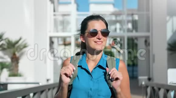 美丽的背包客旅行女孩太阳镜漫步室外棕榈度假酒店背景视频的预览图