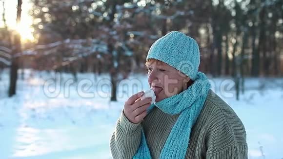 女人在冬天的森林里吃雪有趣的高级女士在户外舔冰作为一个穿着温暖衣服的笑话视频的预览图