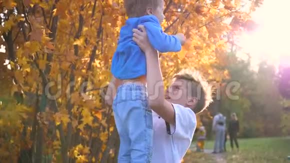 一个青少年和一个孩子玩把他抱在怀里吐出来太阳阳光透过孩子他的笑声和欢乐视频的预览图