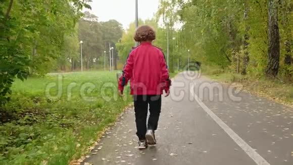 小男孩在夏天的公园里散步同时开始下雨后景少年少年走在秋天的小路上视频的预览图