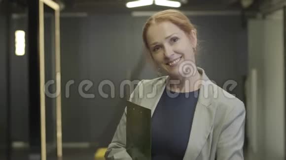 镜头接近漂亮的中年白人妇女穿着正式的衣服站在开放空间办公室女性视频的预览图