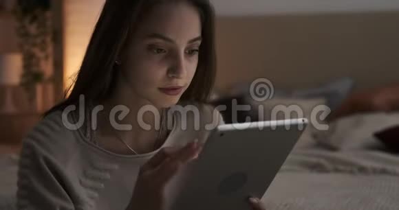 令人震惊的少女晚上使用数码平板电脑视频的预览图