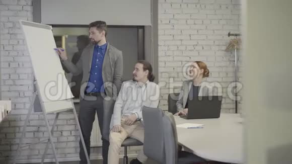 成年白种人头发灰白在空地办公室向他的同事展示着船上的图形坐着的牛仔视频的预览图