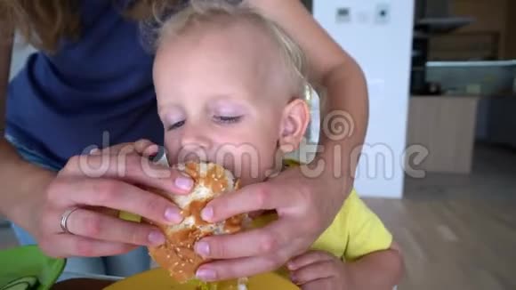 妈妈用汉堡包喂她两岁的儿子万向节运动视频的预览图
