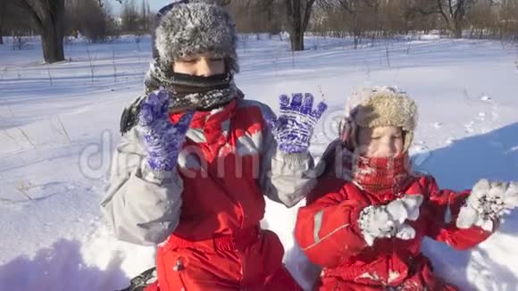 冬天公园里的两个孩子表现出粘稠的雪光视频的预览图