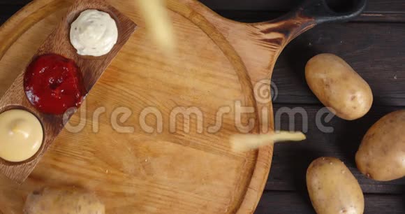 薯条和酱汁一起落在切割板上视频的预览图