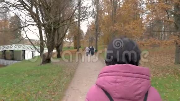 阴云密布的秋日公园女人走在公园的小路上前方有人视频的预览图