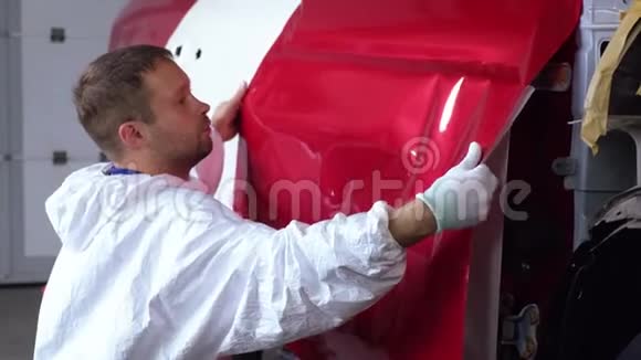 在修理过程中工人正在用胶带盖住汽车的门视频的预览图