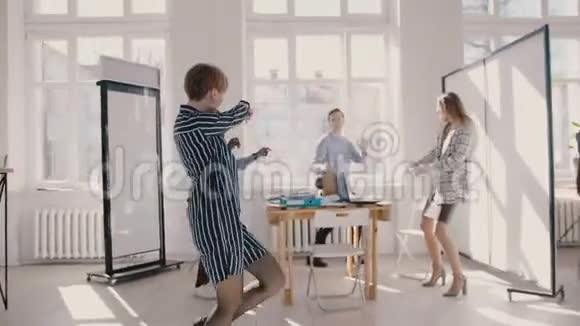 年轻快乐的女办公室工作人员和多民族的同事在有趣的公司聚会上跳舞慢动作视频的预览图