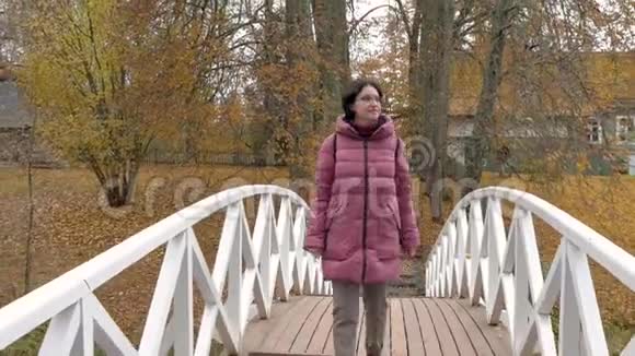 多云的秋天公园白种人女人黑发女人走在桥上视频的预览图