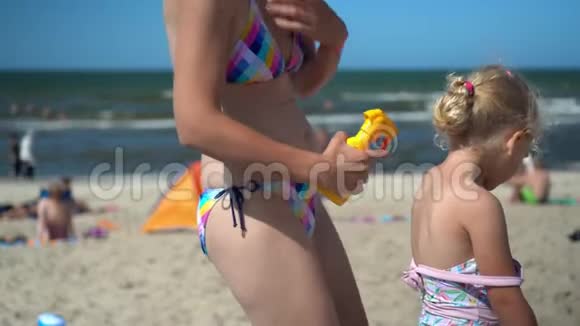 母亲穿比基尼在女儿背上涂防晒霜视频的预览图
