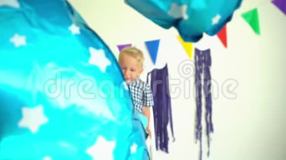快乐的两岁男孩坐在椅子上用气球庆祝二岁生日视频的预览图