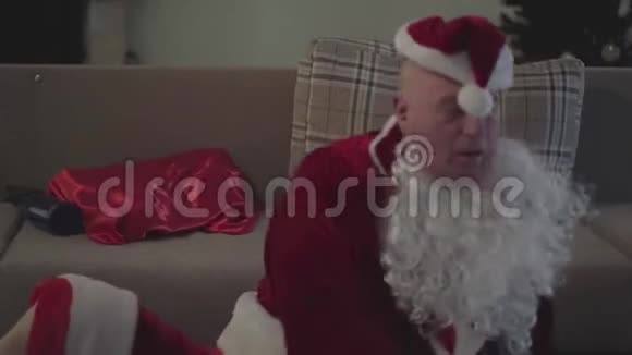 极度醉醺醺的白人老人穿着圣诞老人的服装爬到沙发上假日过后的坏圣诞老人视频的预览图