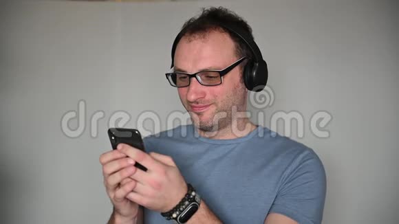 快乐男人在听耳机音乐时使用手机视频的预览图