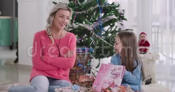 积极的白人金发母亲与女儿交谈作为孩子看礼物盒圣诞快乐女孩视频的预览图