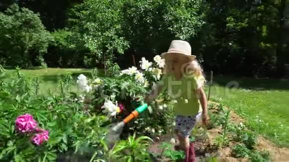 小女孩在花园里用喷雾器浇花万向节运动视频的预览图